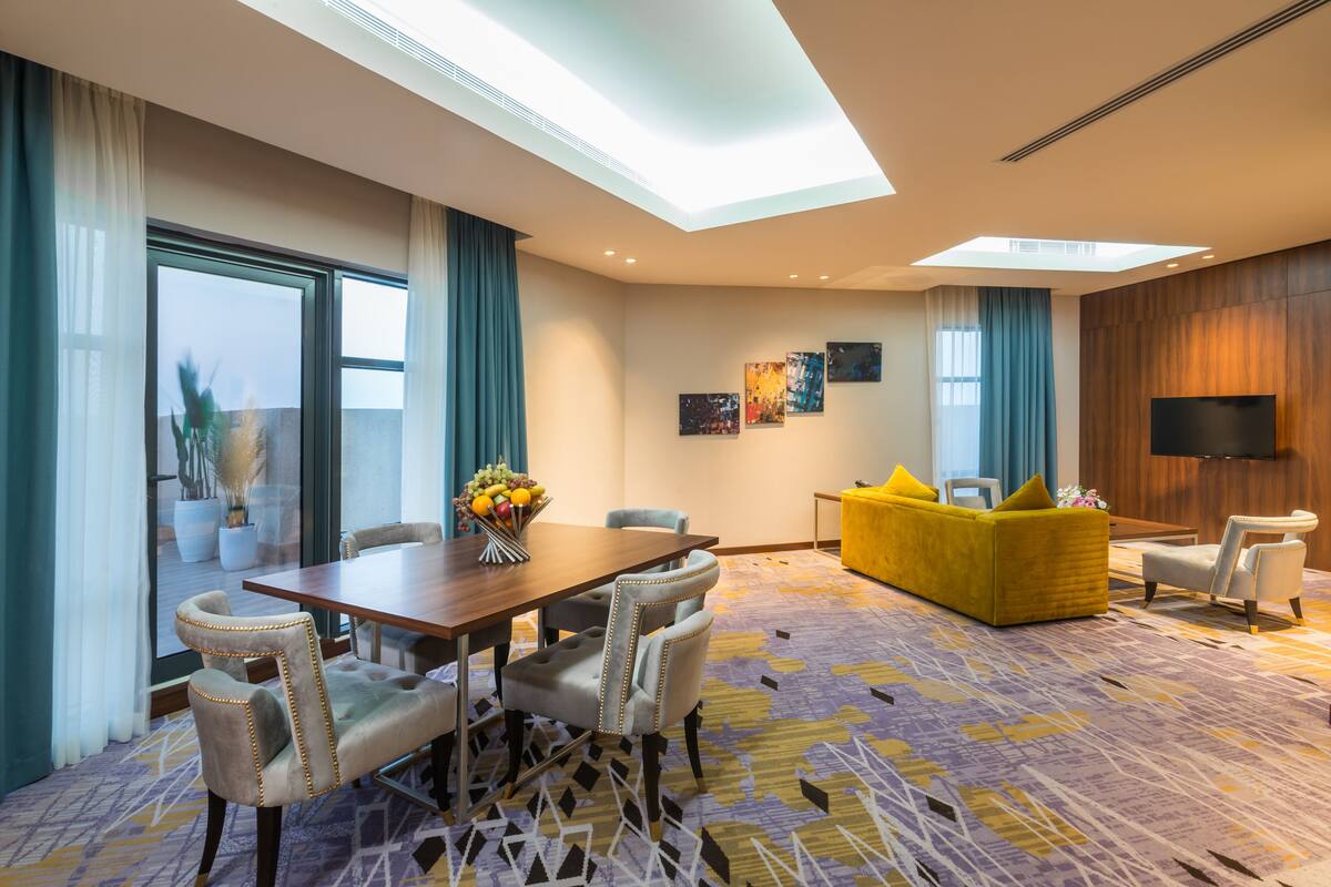 Une chambre d’hôtel avec un coin repas, un canapé et une télévision.