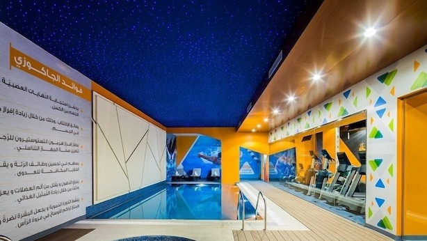 A swimming pool area with a starry ceiling, a hot tub, and exercise equipment.