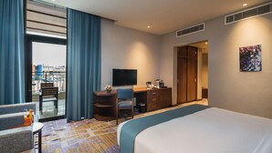 Ein Hotelzimmer mit Bett, Schreibtisch, Stuhl, Fernseher und Blick ins Freie.