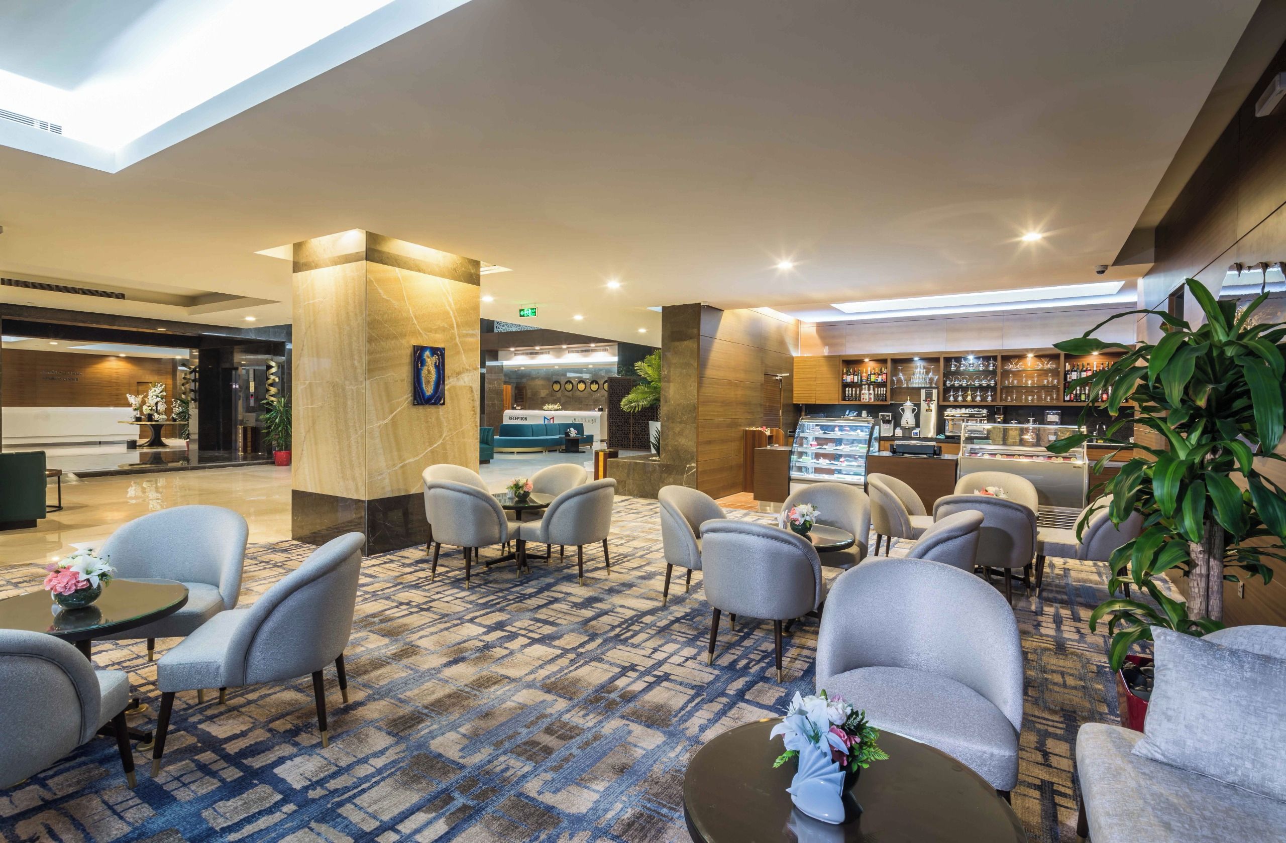 A hotel lobby with seating areas, a reception desk, and a bar.