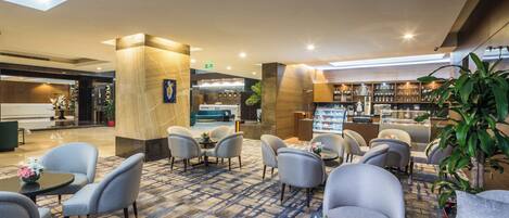 A hotel lobby with seating areas, a reception desk, and a bar.