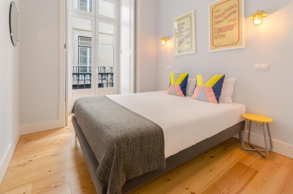 A bedroom with a bed, a small stool, and two wall-mounted light fixtures.