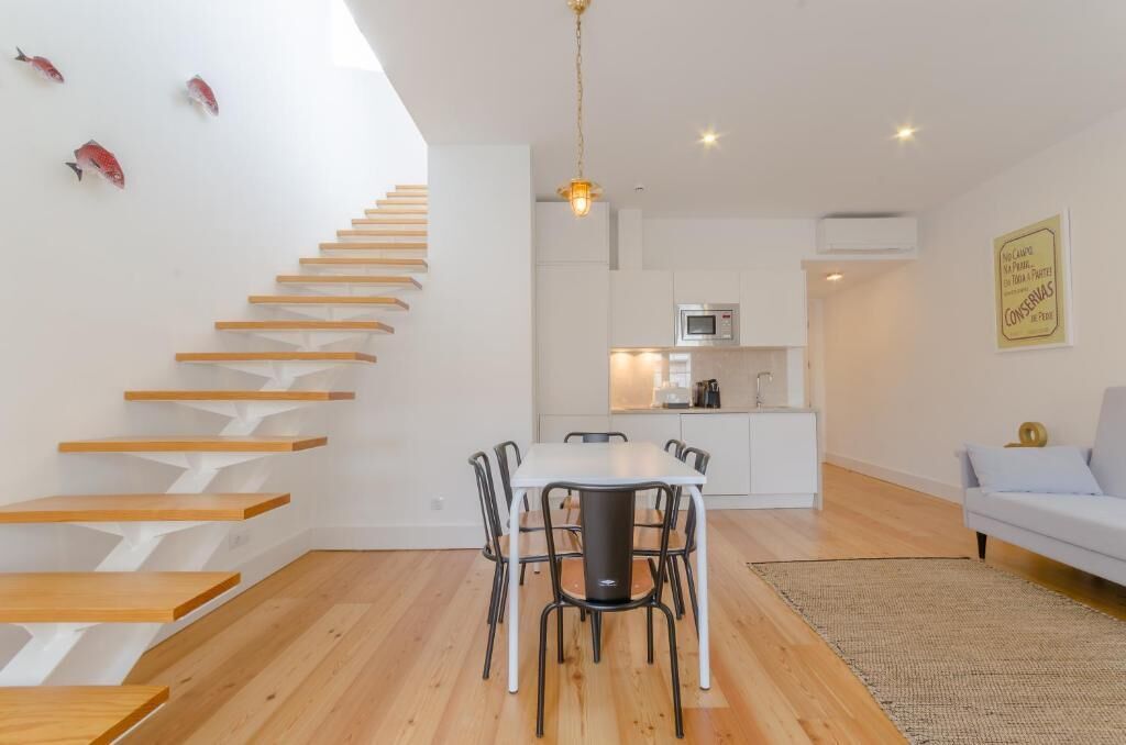 Un intérieur moderne comprenant un escalier, un coin repas, une cuisine et un espace de vie.