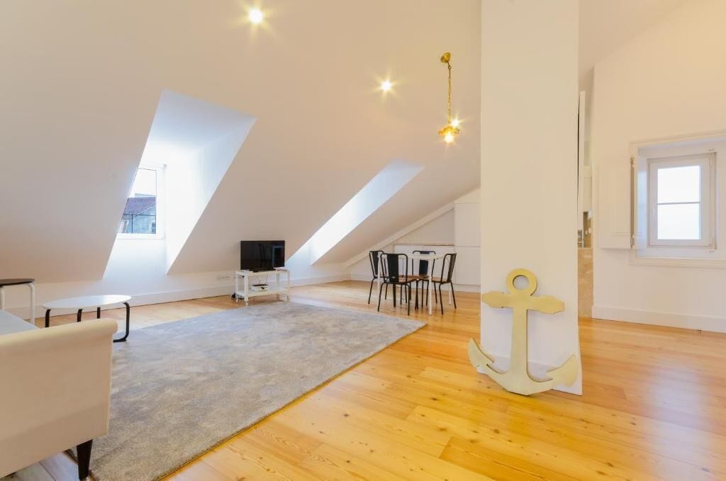 Un appartement-loft spacieux avec de hauts plafonds, une grande fenêtre, un coin repas et un espace salon confortable.