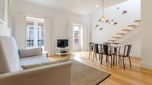 Ein modernes Wohnzimmer mit Sofa, Fernseher, Essbereich und einer Treppe mit einer einzigartigen Fischdeko.