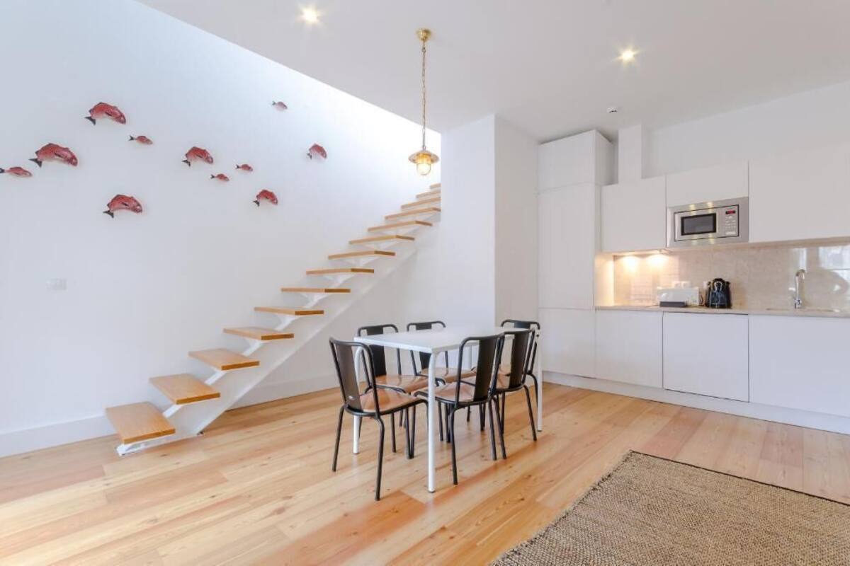 Una cocina moderna con armarios blancos, un microondas y un comedor con mesa y sillas.