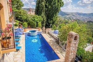 Una piscina al aire libre, sombrillas, sillones reclinables de piscina