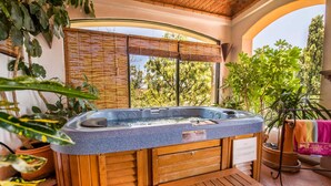 A hot tub with wooden benches, surrounded by potted plants and a view of trees. - Casa Estrella Valenciana Hotel Boutique (Guanajuato)