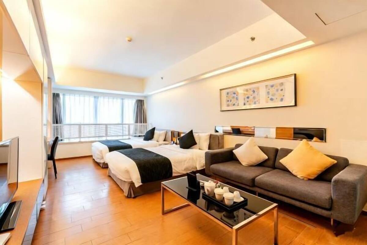 A modern hotel room with a large bed, a sofa, a coffee table, and a TV.