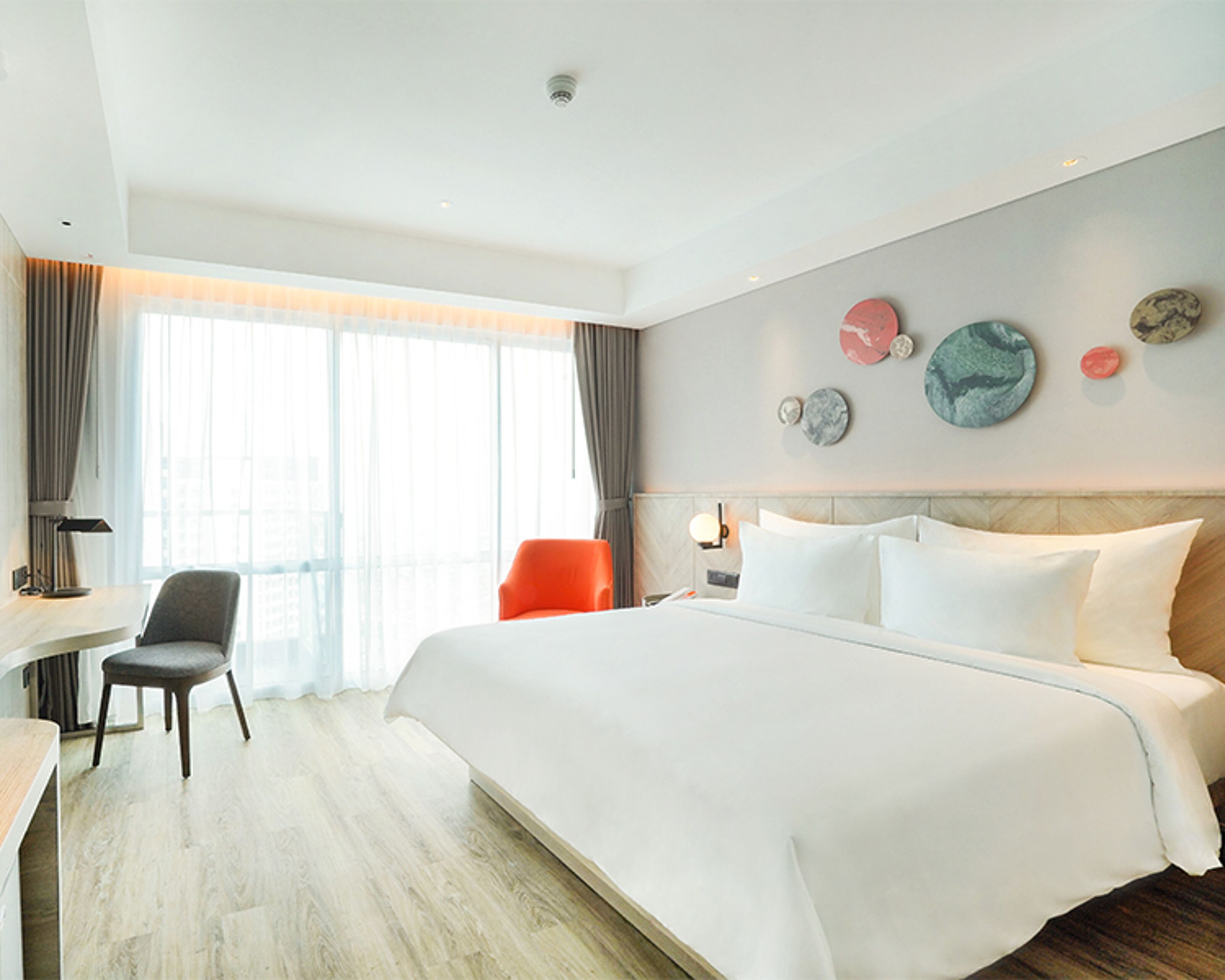 Una habitación de hotel moderna con una cama grande, un escritorio y una silla.