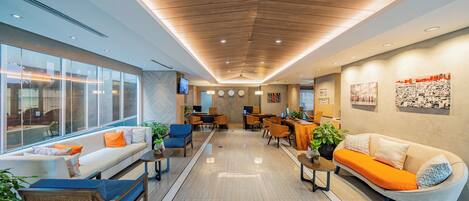 A modern lobby with a sofa, chairs, a coffee table, and a reception desk.