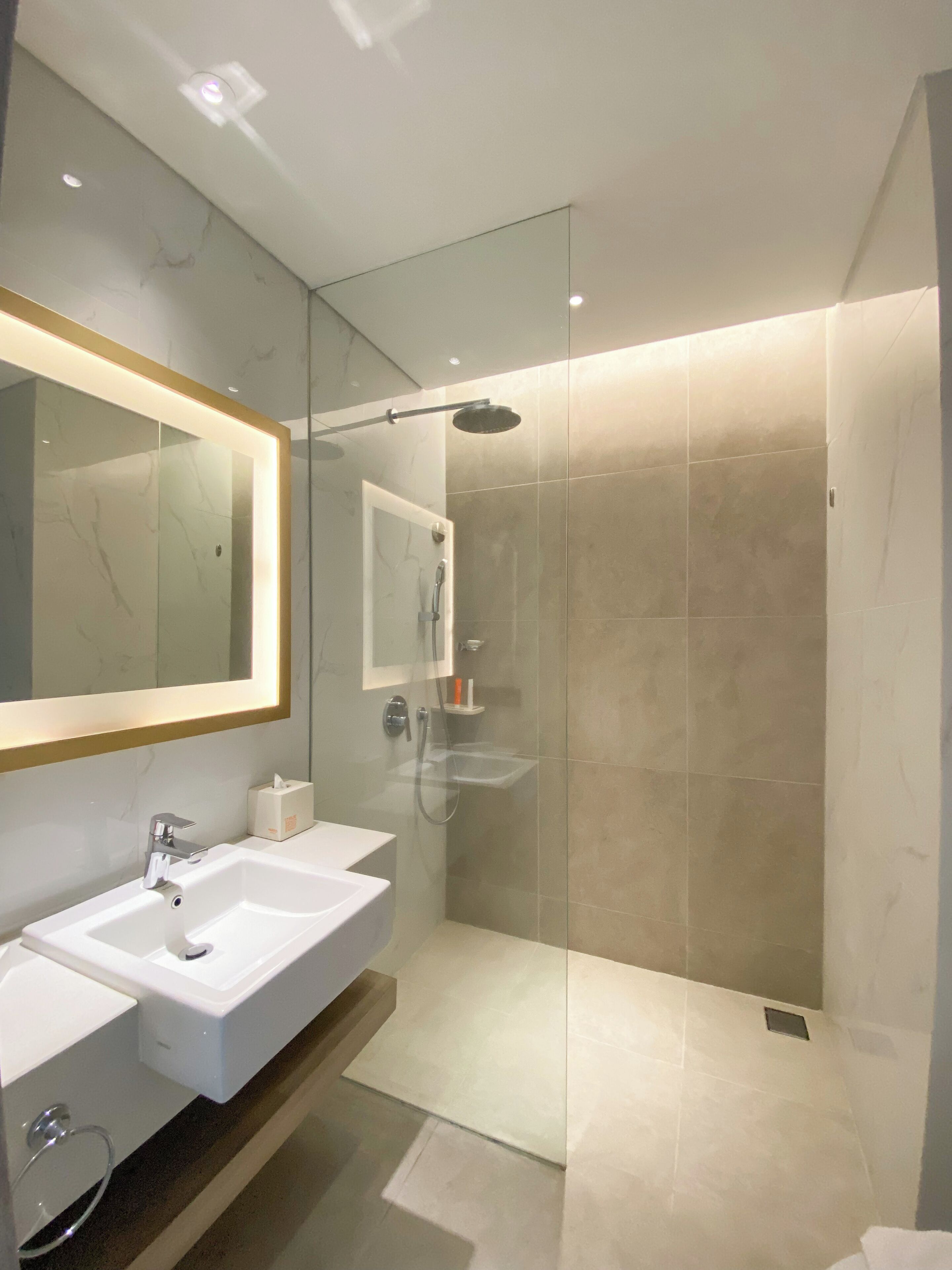 Ein modernes Badezimmer mit zwei Waschbecken, einem großen Spiegel und einer Dusche mit Glaswand.