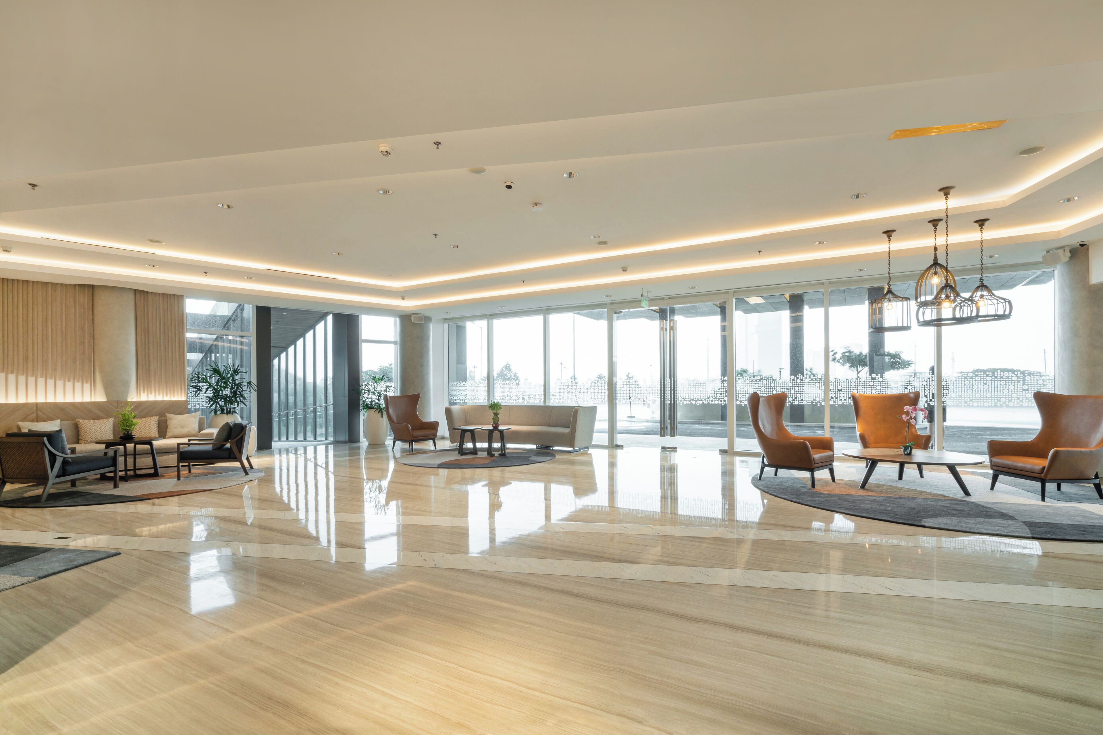 A spacious lobby with a polished floor, modern furniture, and large windows offering a view of the outside.