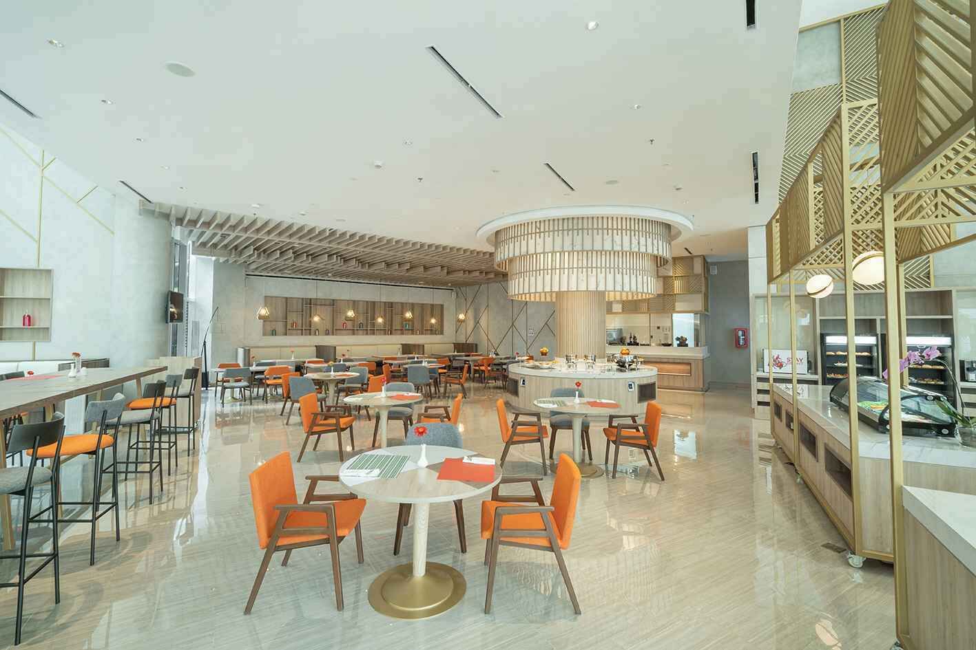 A spacious hotel lobby with multiple seating areas, a central bar, and a display of luxury cars.