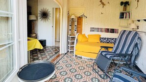 A cozy living room with a patterned floor, a yellow sofa, a striped armchair, and a small round table.