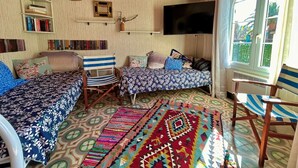A cozy room with two beds, a TV, and a large window.