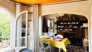 A dining area with a table set for two, a wooden ceiling, and a view of the outdoors.