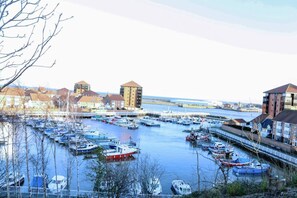 A marina with numerous boats docked, surrounded by buildings with distinct architectural styles. - Beautiful 5-bed House Roker Beach (Sunderland)