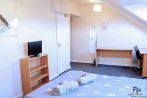 Une chambre à coucher comprenant un lit, un bureau, une chaise, une télévision et une armoire.