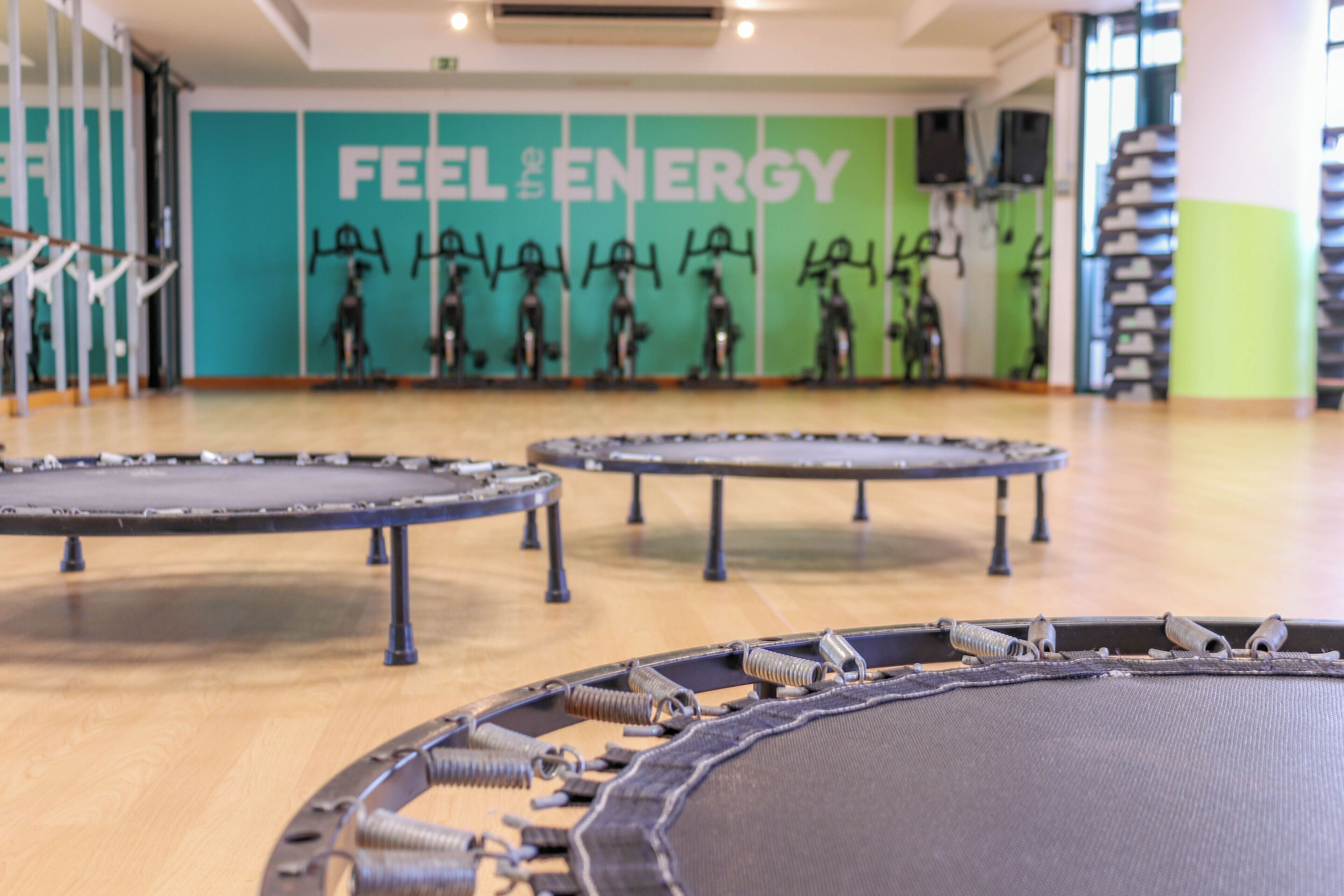 Ein Trampolinbereich mit mehreren Trampolinen und einer Wand mit dem Schriftzug 'FEEL THE ENERGY'.