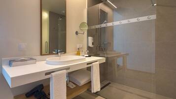 Un baño moderno con un espejo grande, un lavabo y una ducha con mampara de vidrio.