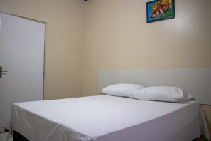 A single bed with white bedding in a room with a plain wall and a door. - Hotel Império (Santarém)