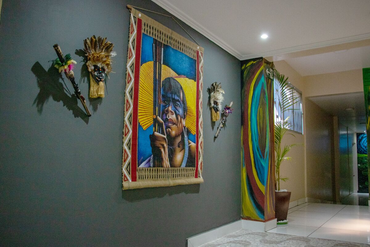 A hallway with a large painting, decorative masks, and a colorful fabric draped over a column.