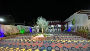 A courtyard with a patterned floor, a central planter with a palm tree, and a building in the background. - Hotel Império (Santarém)