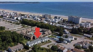 An aerial view of a coastal town with a beach, residential buildings, and a large red arrow pointing to a specific building. - Close to Pier and Downtown | Everything Included | Relax & Enjoy (Old Orchard Beach)