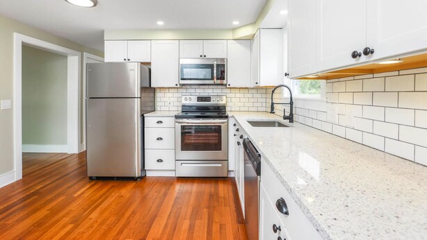A modern kitchen with white cabinets, stainless steel appliances, and a granite countertop. - Close to Pier and Downtown | Everything Included | Relax & Enjoy (Old Orchard Beach)