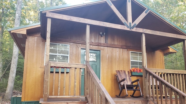 Eine Holzhütte mit einer Veranda, einem Schaukelstuhl und einer Treppe zum Eingang.
