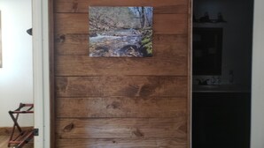 Eine Holzwand mit einem Bilderrahmen, der einen Waldbach zeigt.