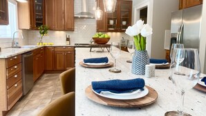 Une cuisine moderne avec des meubles en bois, un îlot central sur lequel est posée une serviette bleue, et un vase rempli de fleurs blanches.