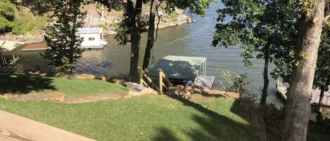 A lakeside deck with a grassy area, a boat dock, and a covered structure.