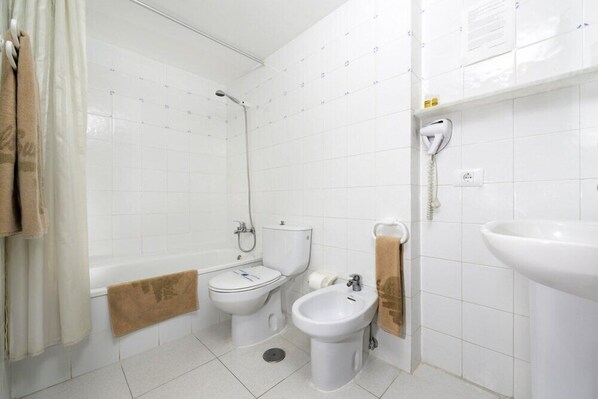 Een badkamer met een bad, toilet, bidet en wastafel.