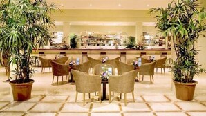 A lobby with a reception desk, several wicker chairs, and potted plants. - Hotel Las Olas (Brena Baja)