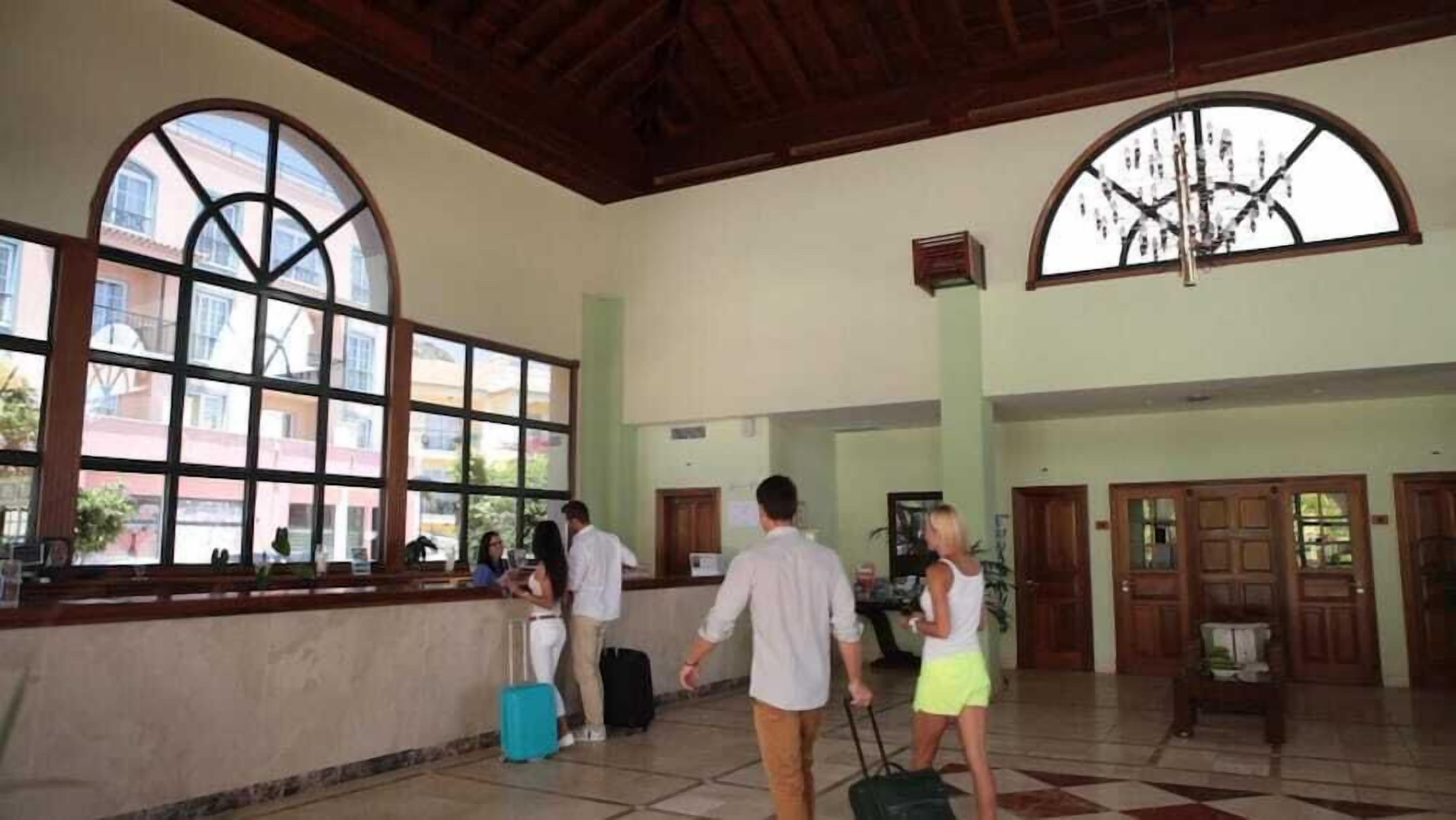 Un vestíbulo espacioso con techos altos, amplias ventanas de arco y un mostrador de recepción.