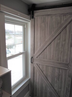 A room with a large window and a wooden barn-style door.