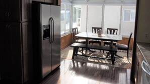 Una cocina con refrigerador de acero inoxidable, armarios de madera y un comedor con mesa y sillas.