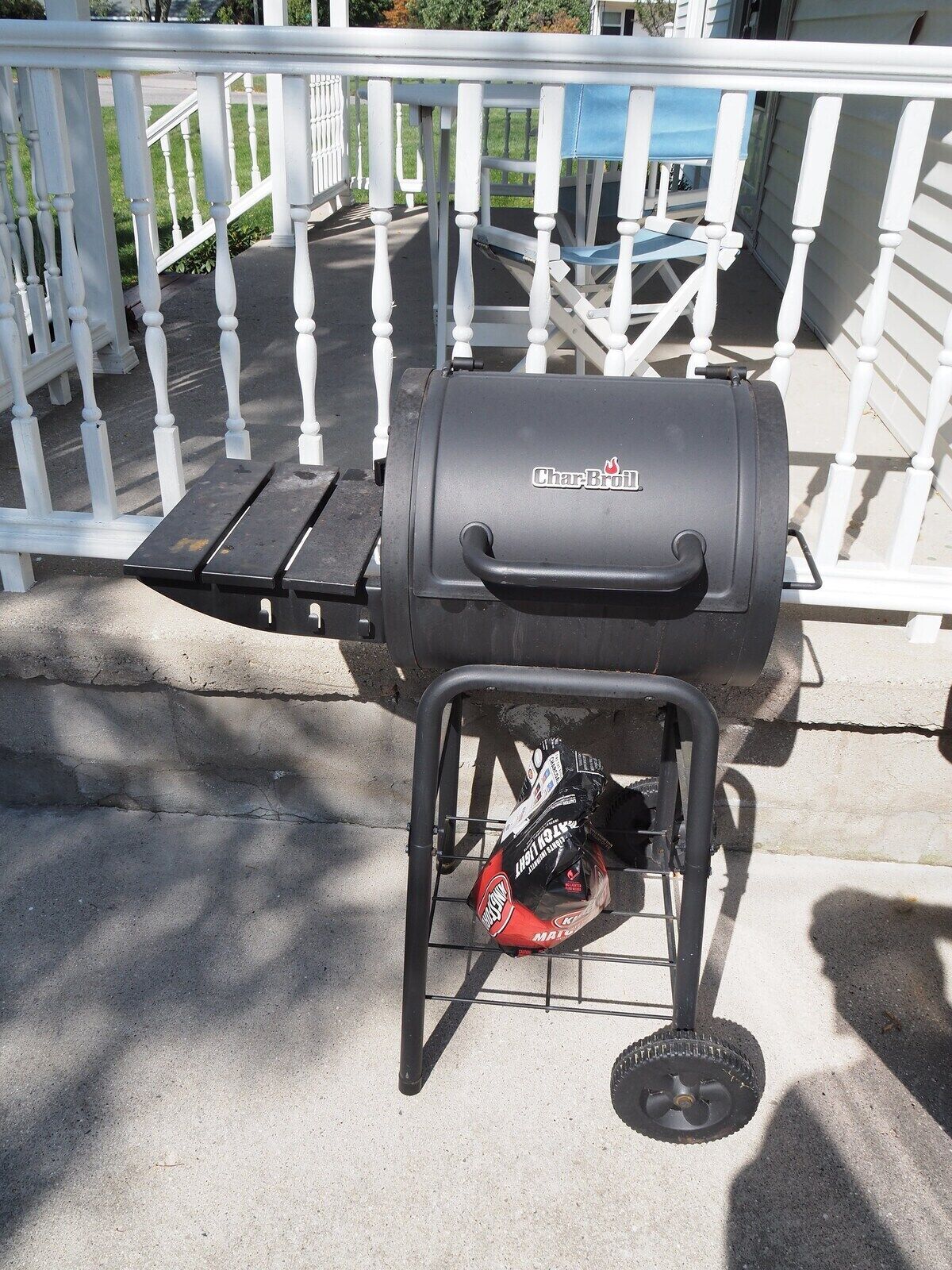 A Char-Broil grill with a side table and a bag of charcoal.