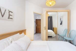 A bedroom with a bed, a wall-mounted sign, a door leading to another room, and a chair.