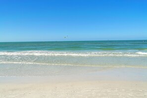 A beach with clear blue water, gentle waves, and a distant sailboat. - Clean & Modern, Close to Beach, Restaurants, Downtown SRQ! (Sarasota)