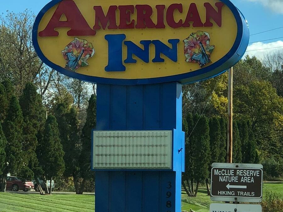 A sign for American Inn with a blue and yellow color scheme, featuring a butterfly and an American flag.