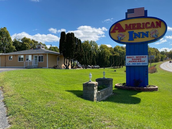 An American Inn sign with a lawn, a small building labeled 'OFFICE', and a road in the background.