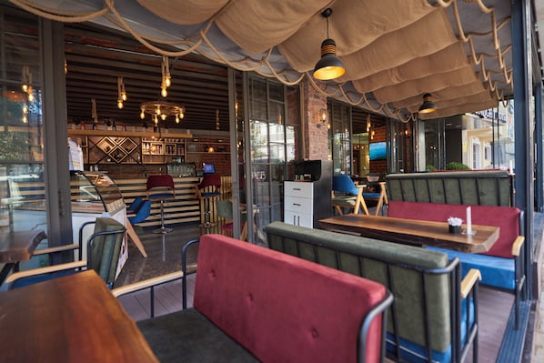 An interior with booths, tables, and a bar area with shelves and a television.