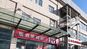 A building with a red sign for a convenience store and a white sign for a business. - Beijing Bincheng Hotel (Tongzhou)