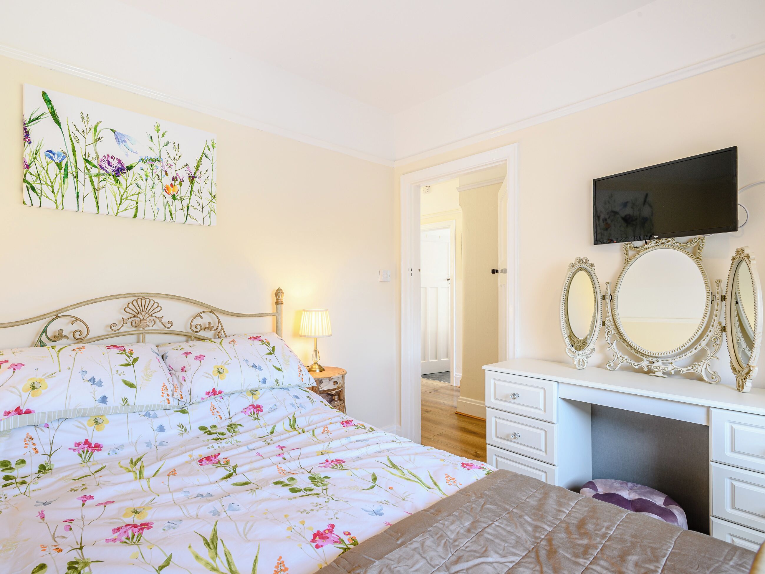 Une chambre à coucher avec un lit, une commode, un miroir et un téléviseur.