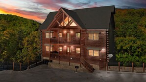 Une cabane en rondins dotée d’un balcon, de nombreuses fenêtres et de fondations en pierre.
