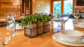 Une table à manger en bois, agrémentée d’un arrangement floral, de verres à vin et d’assiettes.