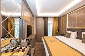 A hotel room with a bed, bedside table with coffee makers, a wardrobe, and a mirror.